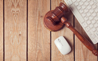 Law gavel and keyboard on wooden background. Online law enforcement concept. View from above